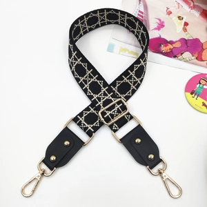 Macro detail of adjustable black ethnic wide bag strap with golden rivet and hardware