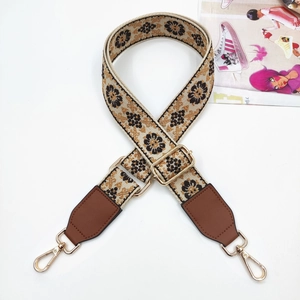 Close-up of ethnic embroidered bag strap with floral patterns and golden metal hooks