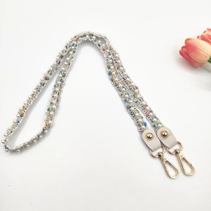 Détail d'une bandoulière tressée multicolore avec perles blanches et fermoir doré