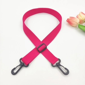 Macro shot of rose red canvas crossbody strap with black plastic lobster clasps and buckle