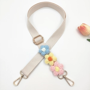Detail of adjustable beige bag strap with handmade 3D crochet flowers and gold hooks