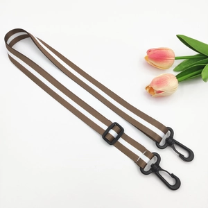 Detail view of adjustable brown and white striped bag strap with black plastic swivel hooks