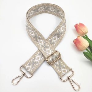 Detail of beige and silver geometric woven strap with gold metal hooks and buckle