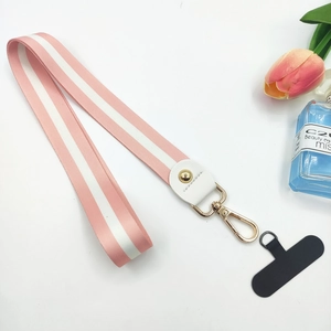 Detailed view of pink and white striped phone lanyard with golden metal clasp and accessories