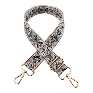 Detailed close-up of ethnic floral embroidery and golden metal hooks on adjustable strap