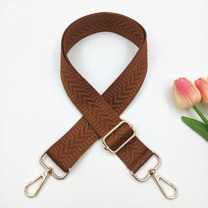 Close-up of caramel brown chevron patterned bag strap with golden metal swivel hooks