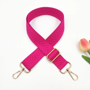 Detail view of rose red purse strap with herringbone weave and gold swivel hooks