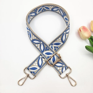 Close-up of jacquard embroidered shoulder strap with blue leaf pattern and gold buckles