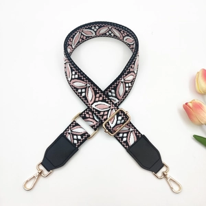 Close-up of ethnic style embroidered bag strap with golden metal buckles and floral pattern
