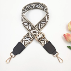 Close-up of adjustable woven shoulder strap with brown floral pattern and gold hooks