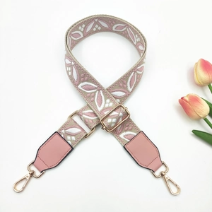 Detail of pink floral embroidered bag strap with adjustable buckle and gold metal hook