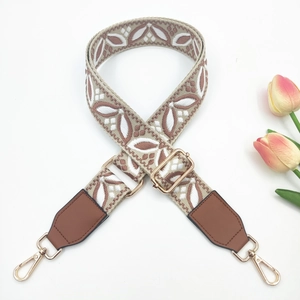 Detail of bohemian geometric floral woven strap with gold metal hooks and brown leather ends