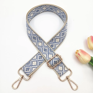 Detail of adjustable geometric diamond pattern bag strap with gold metal buckles
