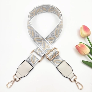 Detail of adjustable woven wide shoulder strap with gray leaf jacquard and gold metal hooks