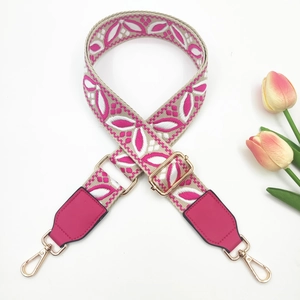 Close-up of pink bohemian embroidered bag strap with golden metal lobster clasps and buckles