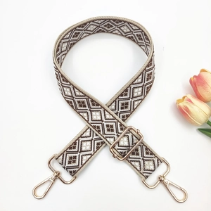 Detail of adjustable geometric weave bag strap with gold metal buckles and swivel hooks