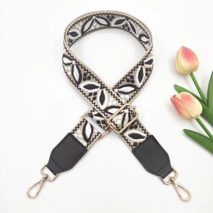 Detail of adjustable wide shoulder strap with black and white leaf pattern and gold hardware