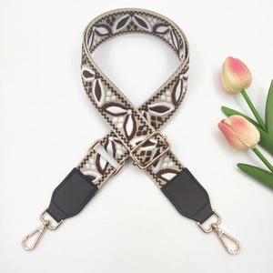 Close-up of ethnic style woven strap with golden metal hooks and floral pattern