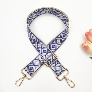 Close-up of geometric pattern blue woven strap with adjustable gold hardware and hooks