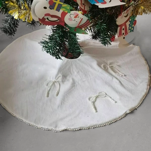 Detail of elegant white Christmas tree skirt with pearl bow accents and soft texture