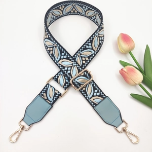 Close-up of ethnic style embroidered strap with floral patterns and gold metal buckles