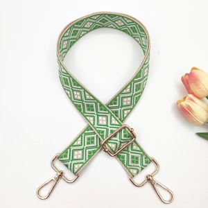 Detail of adjustable geometric weave bag strap with golden lobster clasps and buckles