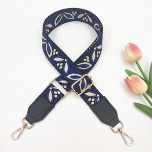 Detail of adjustable woven wide strap with leaf pattern and gold metal hooks