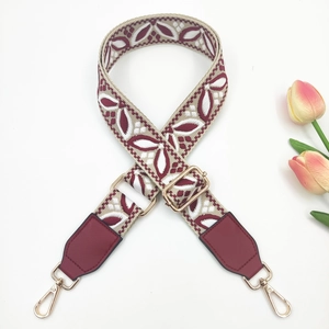 Macro view of burgundy bohemian embroidery and golden metal hooks on wide bag strap