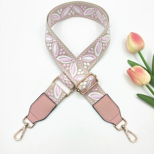 Close-up of pink floral embroidery bag strap with adjustable golden metal buckle