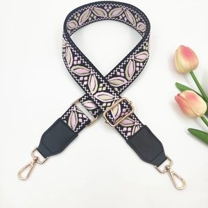 Detail of wide pink and beige leaf embroidered shoulder strap with golden metal clasps
