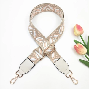 Close-up of adjustable embroidery bag strap with floral patterns and golden metal buckles