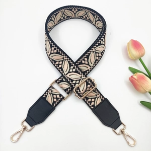 Close-up of ethnic style jacquard shoulder strap with gold metal hooks and leather detail