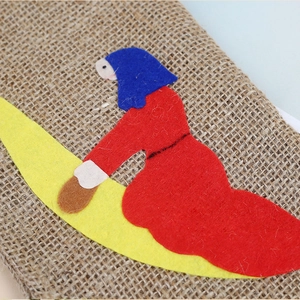 Close-up of rustic jute Christmas stocking with colorful handmade felt figure applique