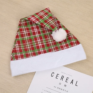 Classic red and green plaid denim Christmas hat with white pom-pom on wooden background