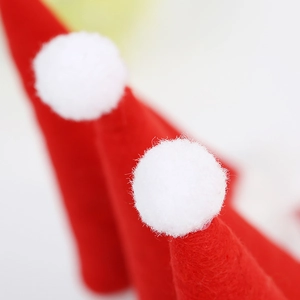 Détail d'une pince à cheveux bonnet de Noël rouge en feutre avec pompon blanc doux