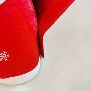 Detail of red Christmas tree skirt showing snowflake print and adjustable hook and loop fastener