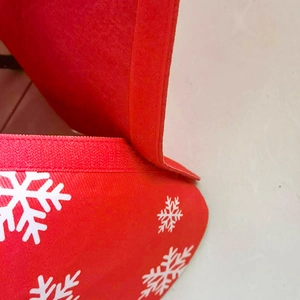 Detail view of red Christmas tree skirt with snowflake print and velcro closure