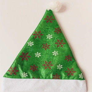 Detail eines grünen Weihnachtshutes mit Schneeflockenprint und weißem Plüsch-Pompon
