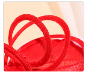 Close-up of vibrant red velvet fabric with white fluffy trim on a Christmas hat decoration