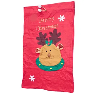 Détail du sac cadeau de Noël rouge avec broderie renne et pompons en peluche blancs