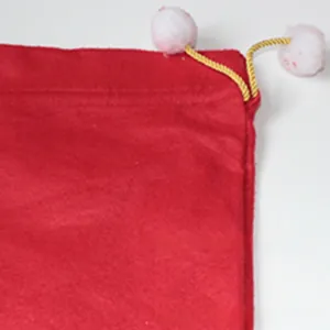 Detail of red felt Christmas gift bag featuring yellow drawstring and white pompoms