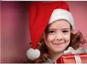 Detailed view of a soft red velvet Santa hat next to a red gift box with white ribbon