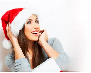 Close-up of a plush red Christmas hat with white faux fur trim held by a model