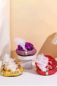 Detail view of Aladdin hats with sequins, white feathers, and pearls in purple, gold, and red