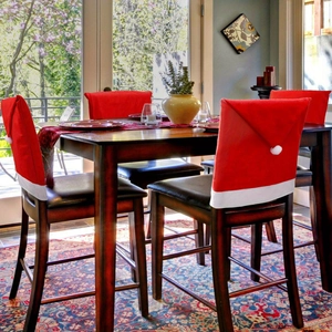 Detail of red non-woven Santa hat chair covers with plush white trim for holiday dining