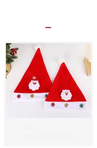 Detail von roten Plüsch-Weihnachtsmützen mit Weihnachtsmann-Aufnähern und bunten Pailletten
