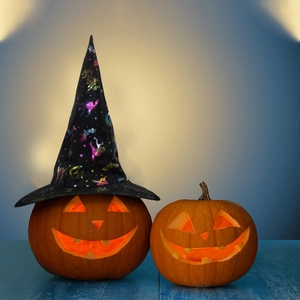Halloween set with glowing Jack-o'-lanterns and black wizard hat on blue wood floor