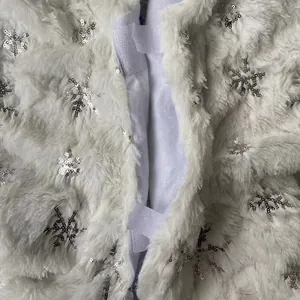 White plush Christmas tree skirt with silver sequin snowflakes and velcro closure