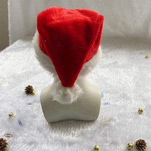 Detail of red plush Christmas hat with gold wire and white faux fur trim on fuzzy rug