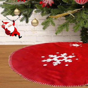 Detail of red Christmas tree skirt with white snowflakes on dark wood floor texture